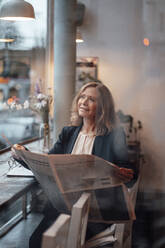 Blond businesswoman sitting with newspaper in cafe - JOSEF05192