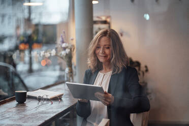 Weibliche Fachkraft mit digitalem Tablet in einem Café sitzend - JOSEF05193