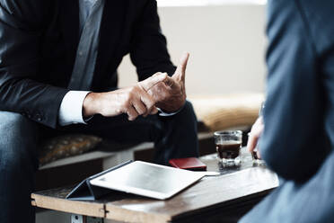 Male professional gesturing while discussing strategy with female colleague sitting in cafe - JOSEF05231