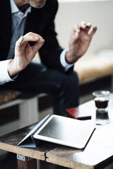 Male professional gesturing while sitting with digital tablet at table in cafe - JOSEF05232