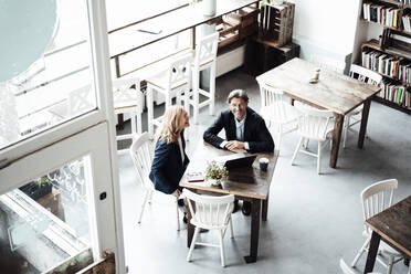 Glückliche männliche und weibliche Fachkräfte sitzen zusammen am Tisch in einem Café - JOSEF05236