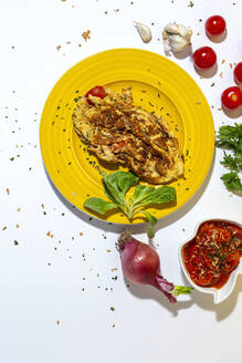 Leckeres Omelett mit gehackter Petersilie auf einem Teller mit sonnengetrockneten Tomaten und rohen roten Zwiebeln auf weißem Hintergrund - ADSF27673