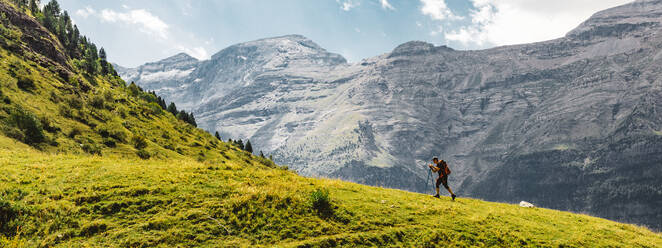 Panoramic side view of unrecognizable men hiking green mountain in the Dolomites, Italy - ADSF27697