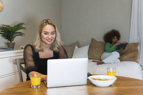Junge Frau arbeitet zu Hause mit einem Freund an einem Laptop - PNAF02058