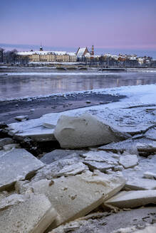 Polen, Woiwodschaft Masowien, Warschau, Eis schwimmend am Flussufer in der Morgendämmerung mit alten Stadtgebäuden im Hintergrund - ABOF00657