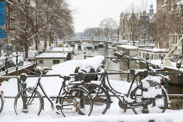 Niederlande, Nordholland, Amsterdam, Fahrräder auf der schneebedeckten Brücke über den Prinsengracht-Kanal - FVDF00347