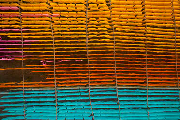 Aerial view of a person working in a public laundry hanging for drying colourful cloth in Narayanganj, Dhaka, Bangladesh. - AAEF10715