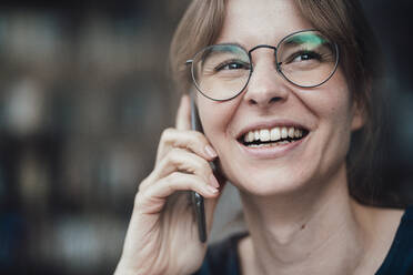 Happy young businesswoman wearing eyeglasses talking on smart phone - JOSEF05263