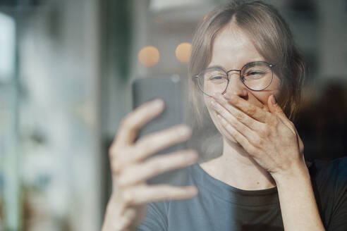 Weibliche Fachkraft bedeckt den Mund während eines Videoanrufs über ein Mobiltelefon - JOSEF05271