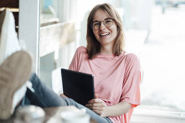 Cheerful female freelancer sitting with digital tablet in cafe - JOSEF05283