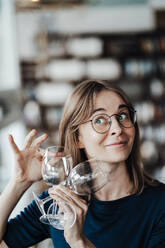 Young woman with brown hair holding wineglasses in cafe - JOSEF05324