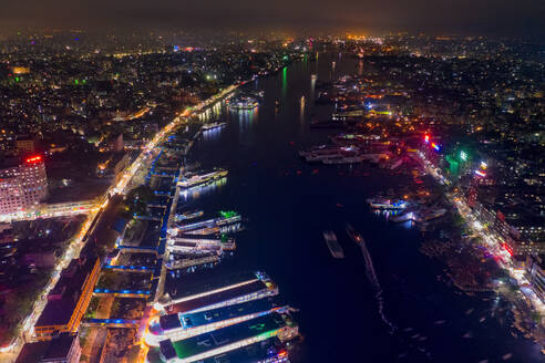 Aerial view of Buriganga river and the Sadarghat Terminal at night with several ships docked with Old Dhaka district in background, Dhaka, Bangladesh. - AAEF10924