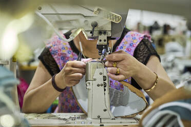 Detail of worker's hands doing sewing in the leather of the shoes at Chinese shoes factory - ADSF27798