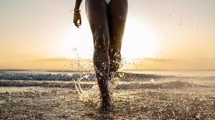 Crop black woman with braids running on the beach - ADSF27803