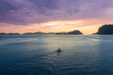 Aerial view outrigger sailing at sunset in the bay of El Nido, the Philippines. - AAEF11228