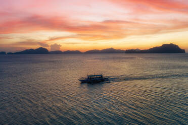 Luftaufnahme eines Auslegerboots bei Sonnenuntergang in der Bucht von El Nido auf den Philippinen. - AAEF11243