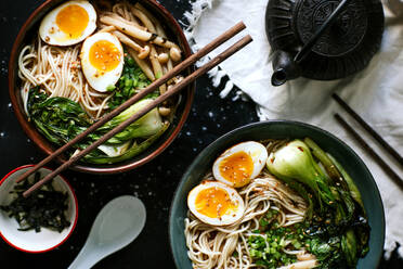 Top view of ceramic bowls with delicious ramen and chopsticks placed on table - ADSF27836