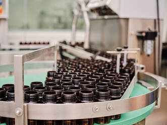 Reihen von leeren Plastikflaschen auf einem Metallband in einer pharmazeutischen Fabrik - ADSF27849