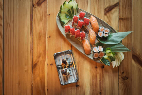 From above gunkan sushi and Uramaki rolls served on plates on wooden table in Japanese restaurant - ADSF27924