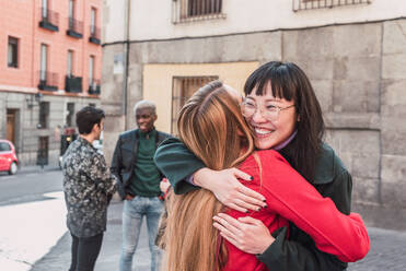 Vergnügte multirassische Freundinnen, die sich umarmen, während sie auf der Straße stehen und das Wochenende genießen - ADSF28019