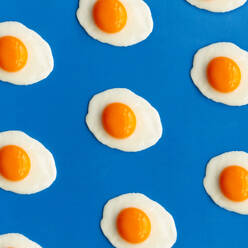 Row of fried eggs on a blue background - ADSF28079