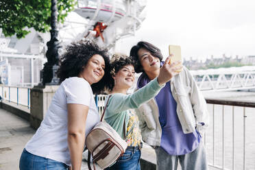 Multi-ethnic friends taking selfie through smart phone - ASGF00859