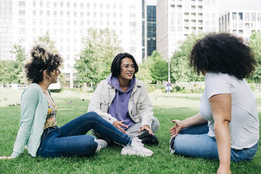 Junger Mann im Gespräch mit multiethnischen Freundinnen im Park - ASGF00864