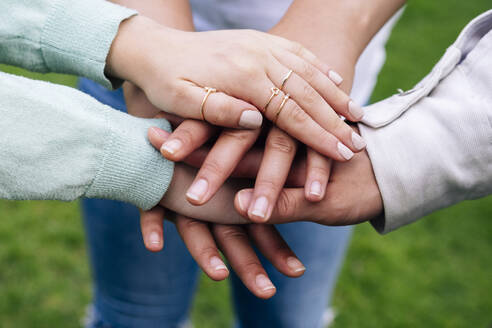 Male and female friends stacking hands - ASGF00896