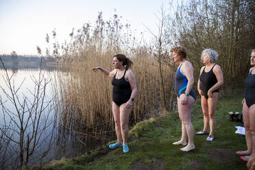 Frauen schauen auf das Wasser, während sie am Ufer stehen - FVDF00359