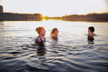 Fröhliche Frauen, die sich im Wasser vergnügen und einen männlichen Freund ansehen - FVDF00387