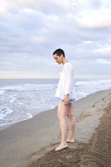Nachdenkliche junge Frau am Strand stehend - VEGF04732