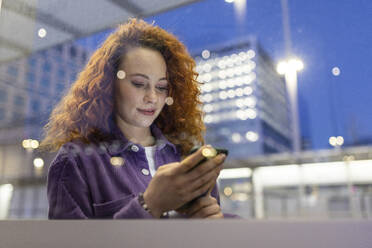 Redhead woman using smart phone at tram station - WPEF05078