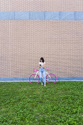 Woman using mobile phone while sitting on bicycle - GIOF13037