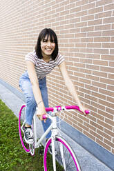 Schöne Frau beim Radfahren an der Wand - GIOF13052