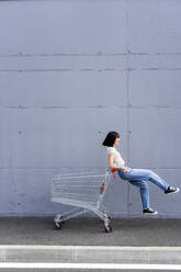 Cheerful woman having fun with shopping cart - GIOF13060