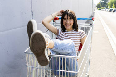 Happy woman sitting in shopping cart - GIOF13062