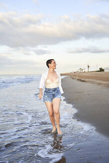 Glückliche Frau beim Spaziergang am Meer - VEGF04743