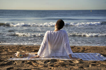 Junge Frau schaut auf den Horizont, während sie sich am Strand entspannt - VEGF04755
