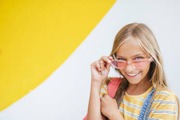 Blondes Mädchen mit Sonnenbrille lächelnd vor einer Wand - JCMF02148
