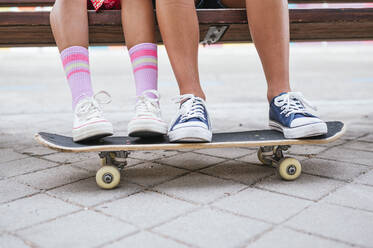 Friends with skateboard sitting on bench - JCMF02159
