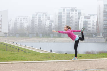 Frau übt Yoga im Stehen im Park - FVDF00413