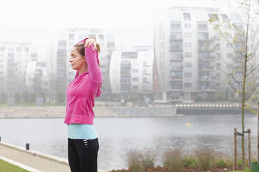 Woman with eyes closed stretching arms at park - FVDF00414