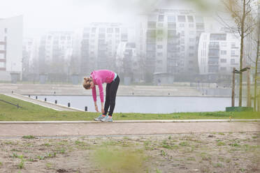 Frau beugt sich beim Sport im Park nach vorne - FVDF00423