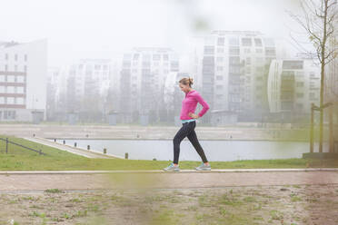 Frau mit Hand auf der Hüfte beim Sport im Park - FVDF00424