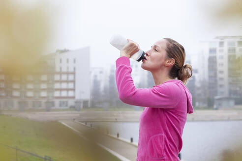 Frau trinkt Wasser in einem Park in der Stadt - FVDF00429