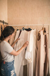 Weibliche Kundin, die in der Werkstatt Kleider auf dem Regal durchsucht - GRCF00767