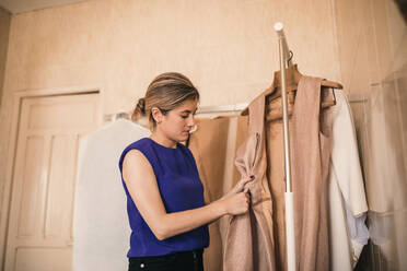 Smiling beautiful female fashion designer standing by dressmaker's model at  atelier stock photo