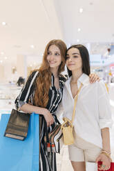 Friends with shopping bags while standing together at mall - JRVF01250