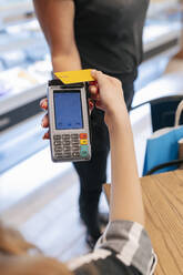 Frau zahlt mit Kreditkarte an Kellnerin im Food Court - JRVF01257