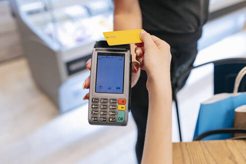 Frau hält Kreditkarte in der Hand, während sie bei einer Kellnerin im Food Court bezahlt - JRVF01258